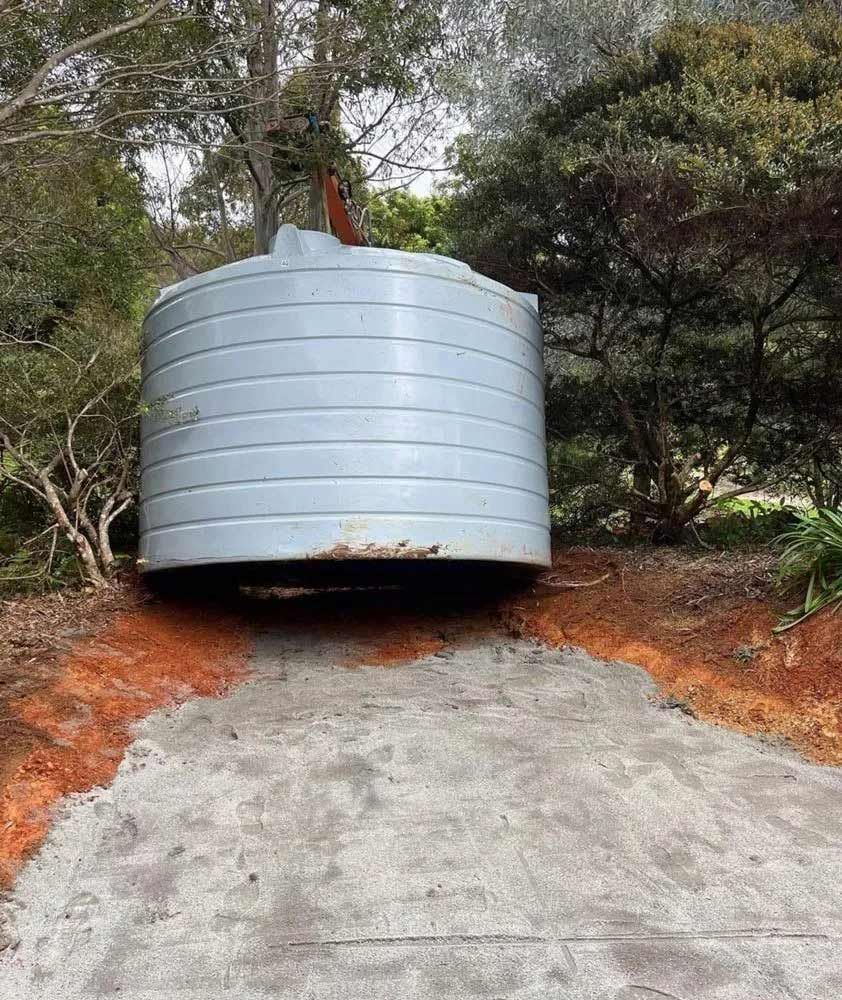 A Large Metal Tank Is Sitting On Top Of A Dirt Hill — Coastal Plumbing Group in Woolgoolga, NSW