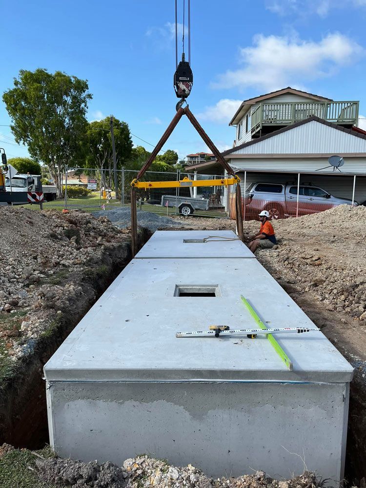 A Large Concrete Block Is Being Lifted By A Crane — Coastal Plumbing Group in Woolgoolga, NSW