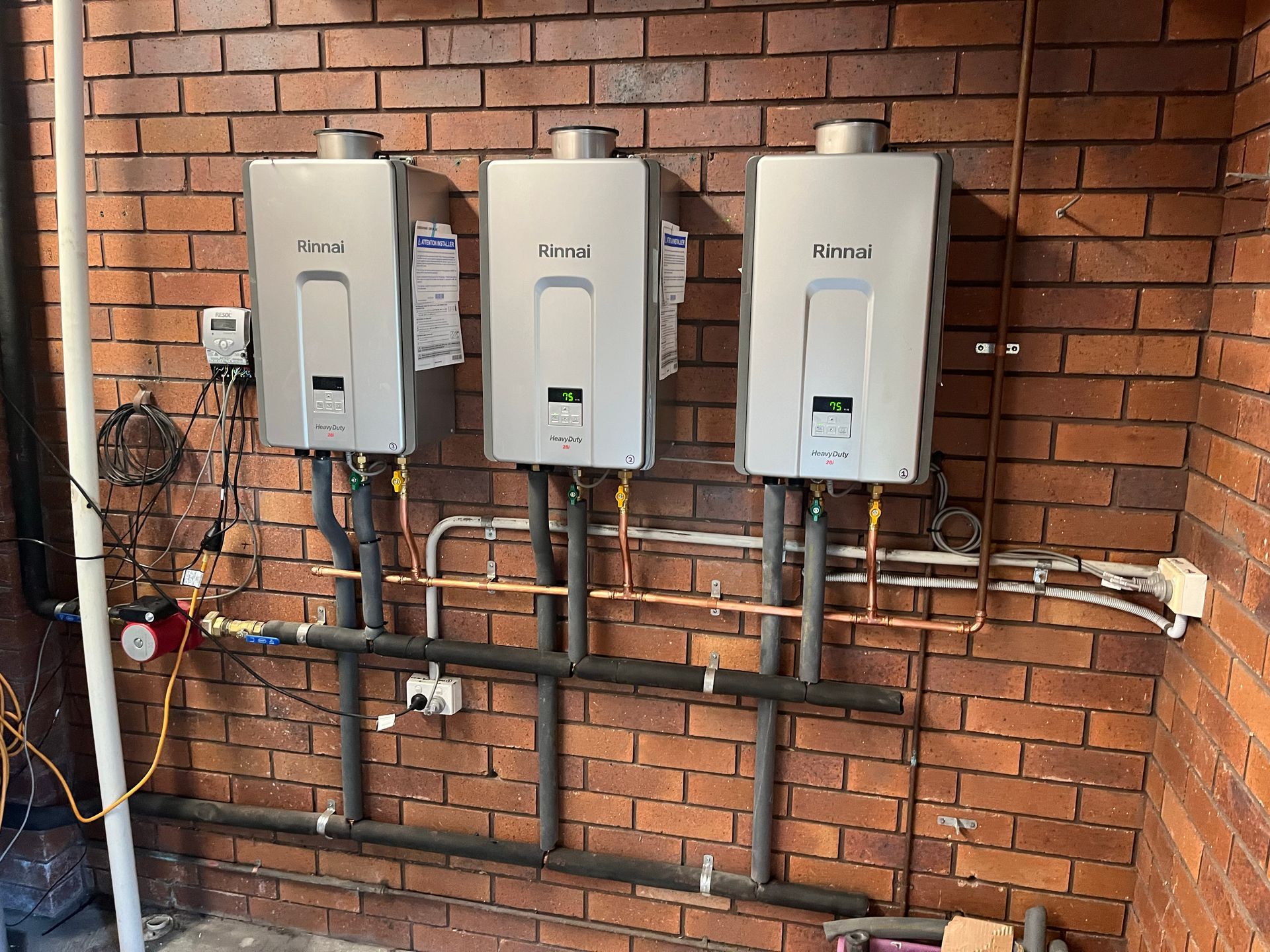A White Water Heater Is Attached To A Brick Wall — Coastal Plumbing Group in Woolgoolga, NSW