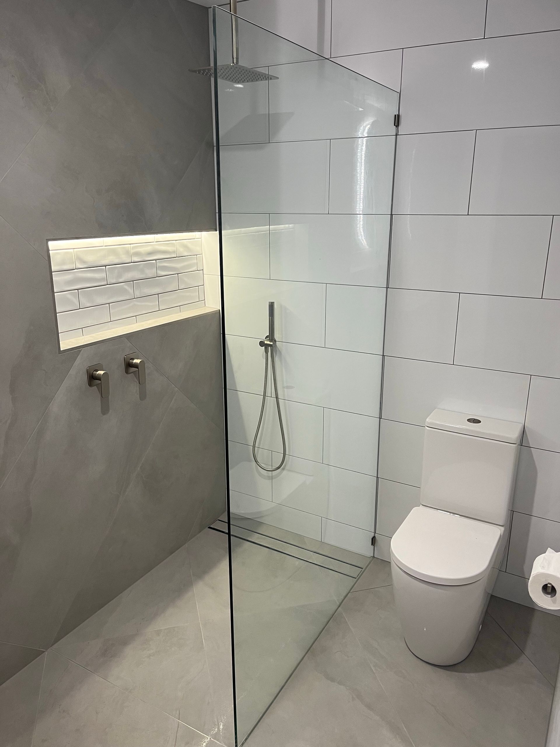 A Man Is Fixing A Bathtub Faucet With A Screwdriver — Coastal Plumbing Group in Woolgoolga, NSW