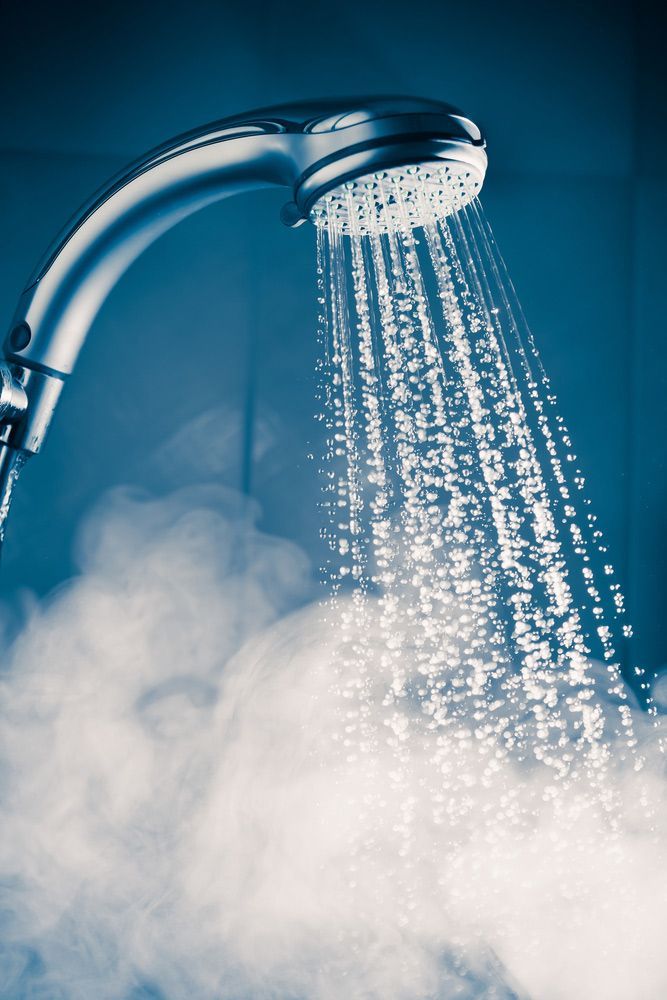 A Shower Head With Steam Coming Out Of It — Coastal Plumbing Group in Woolgoolga, NSW
