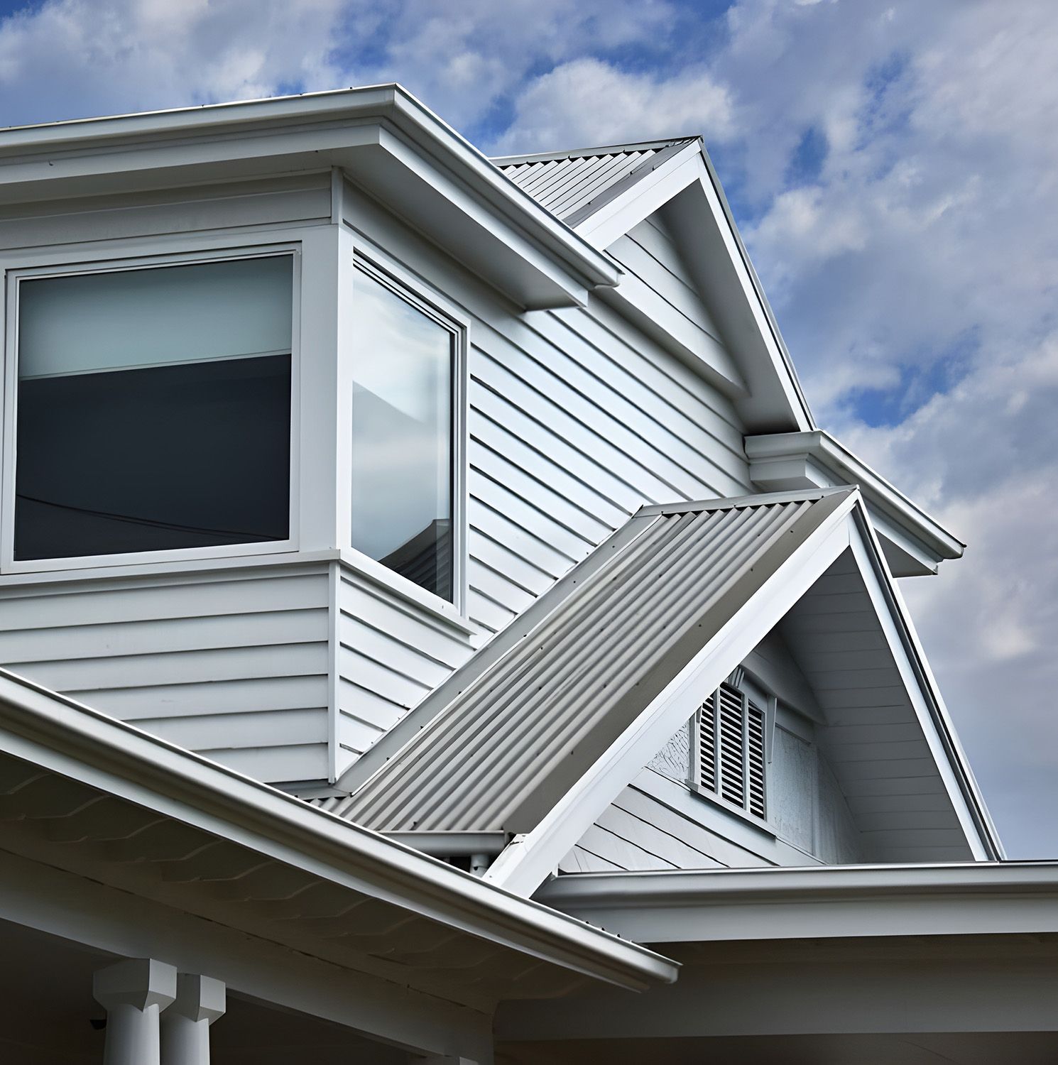 A Light Gray, Two-Story House With A Metal Roof — Roof Repairs Coffs Harbour -Coastal Plumbing Group in Woolgoolga, NSW