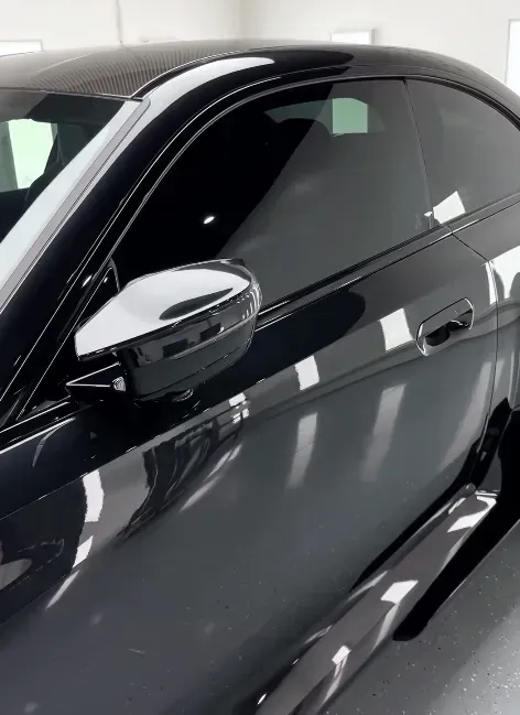 A black car is parked in a garage with new tints.