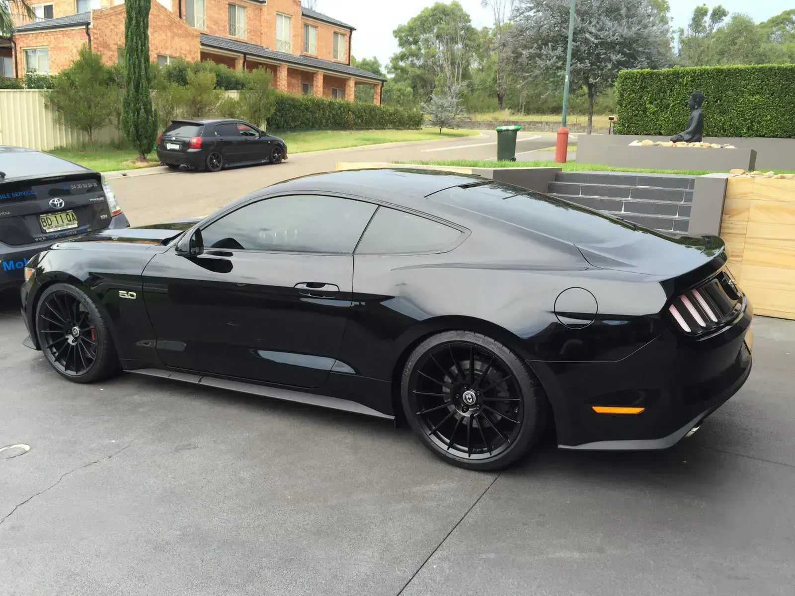 A black ford mustang is parked in a parking lot ready for window tinting service.