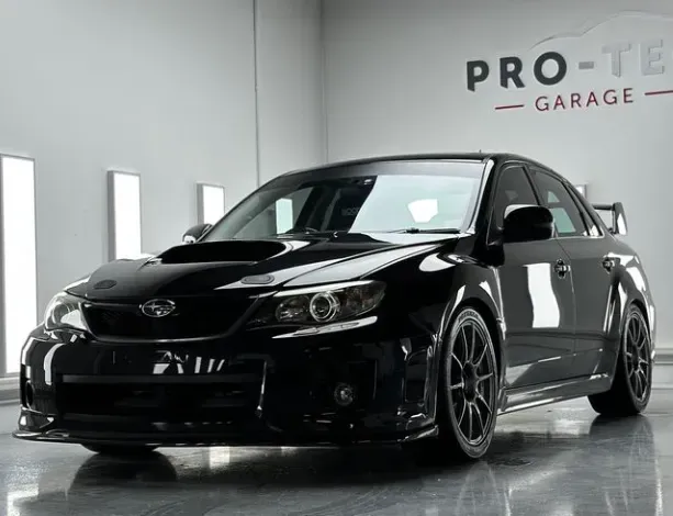 A black subaru wrx sti is parked in a garage with new tinting project completed.