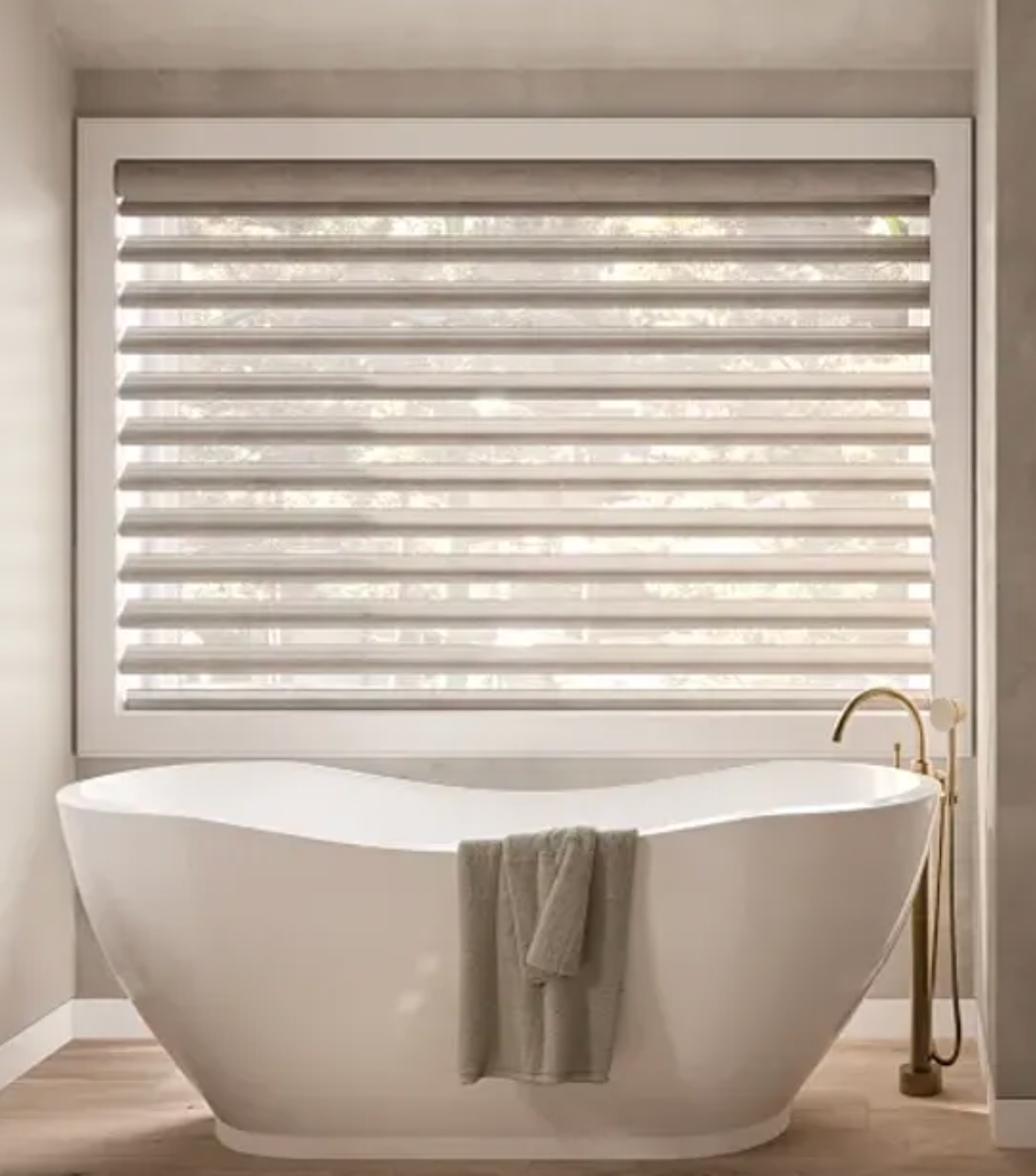 Bathroom with white soaking tub, layered Hunter Douglas Pirouette window shades, and gold faucet.