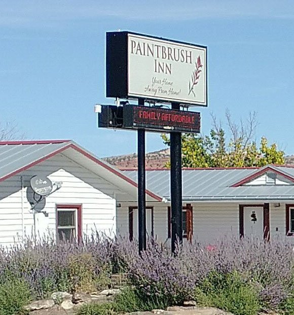 A sign for paintbrush inn is in front of a white house