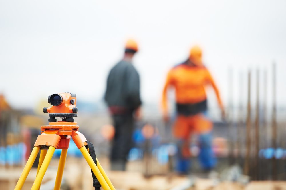 A Construction Site With Workers In The Background And A Tripod In The Foreground  — CalCo Surveyors Pty Ltd in Gloucester, NSW