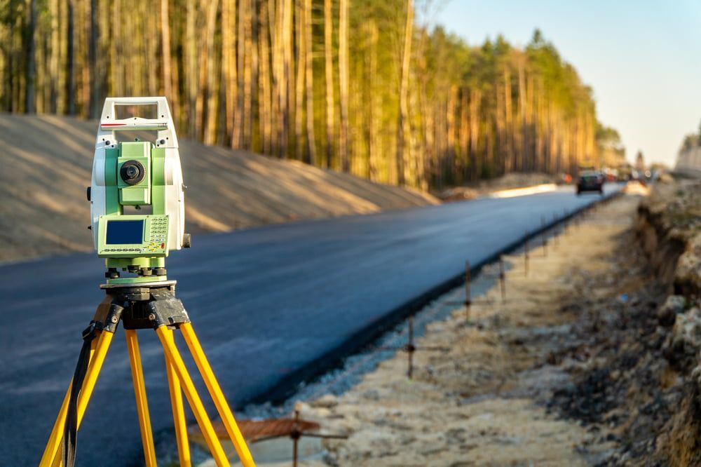 A Total Station Is Sitting On A Tripod On The Side Of A Road  — CalCo Surveyors Pty Ltd in Diamond Beach, NSW