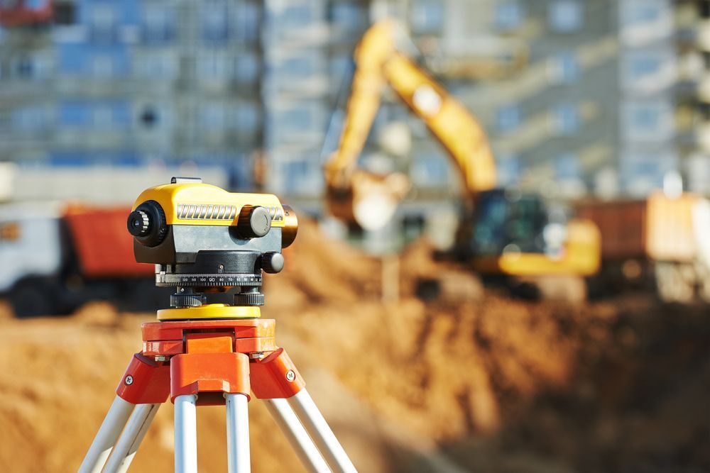 A Level Is Sitting On A Tripod At A Construction Site With A Bulldozer In The Background  — CalCo Surveyors Pty Ltd in Diamond Beach, NSW