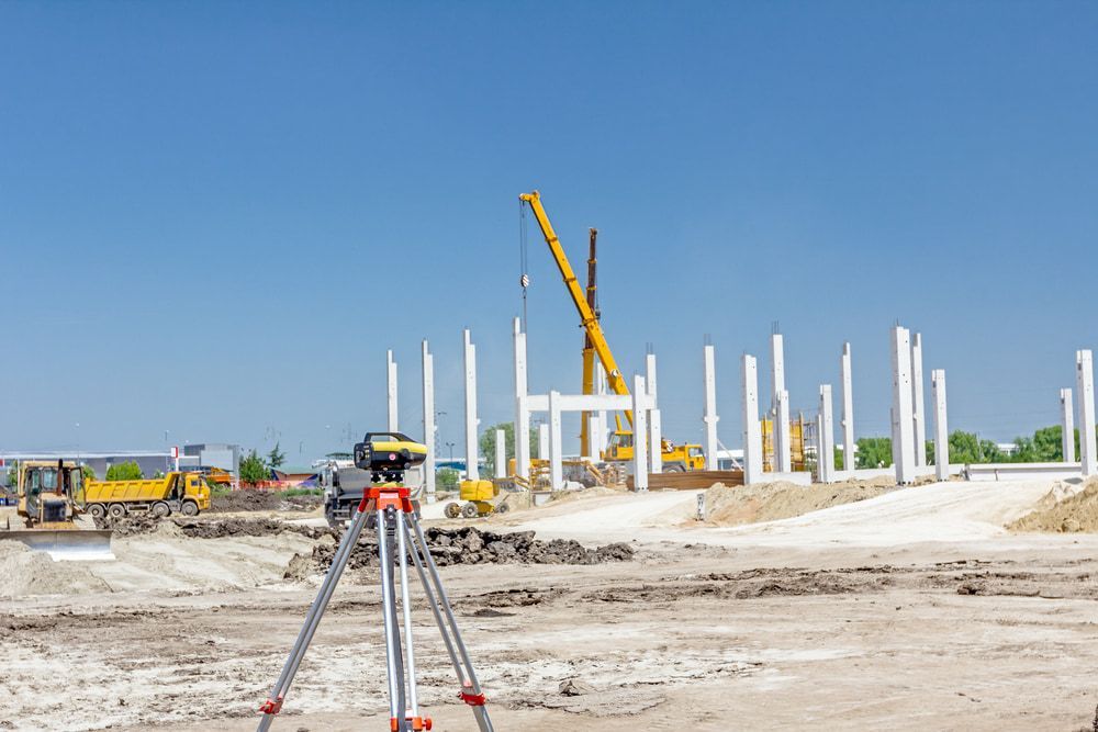 A Construction Site With A Level On A Tripod In The Foreground And A Crane In The Background  — CalCo Surveyors Pty Ltd in Forster, NSW