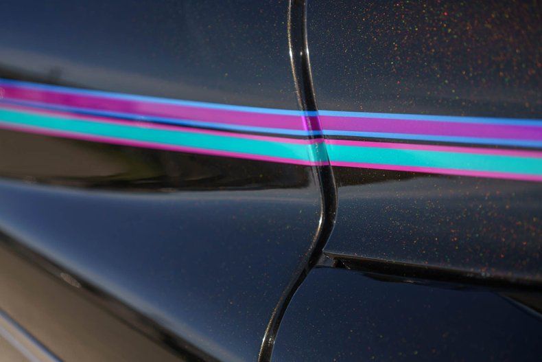 A black car door panel featuring horizontal stripes in shades of bright purple and turquoise.
