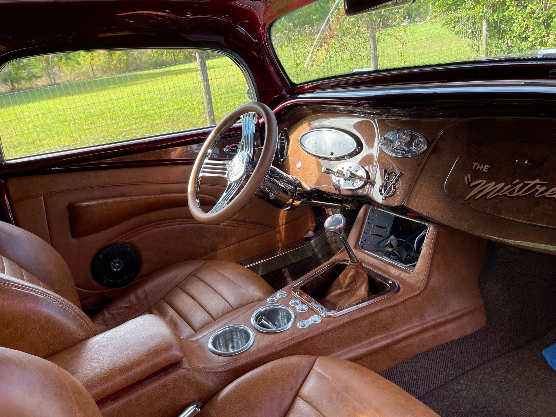 Interior view of a classic car with brown leather bucket seats, a custom center console, and a vintage steering wheel.