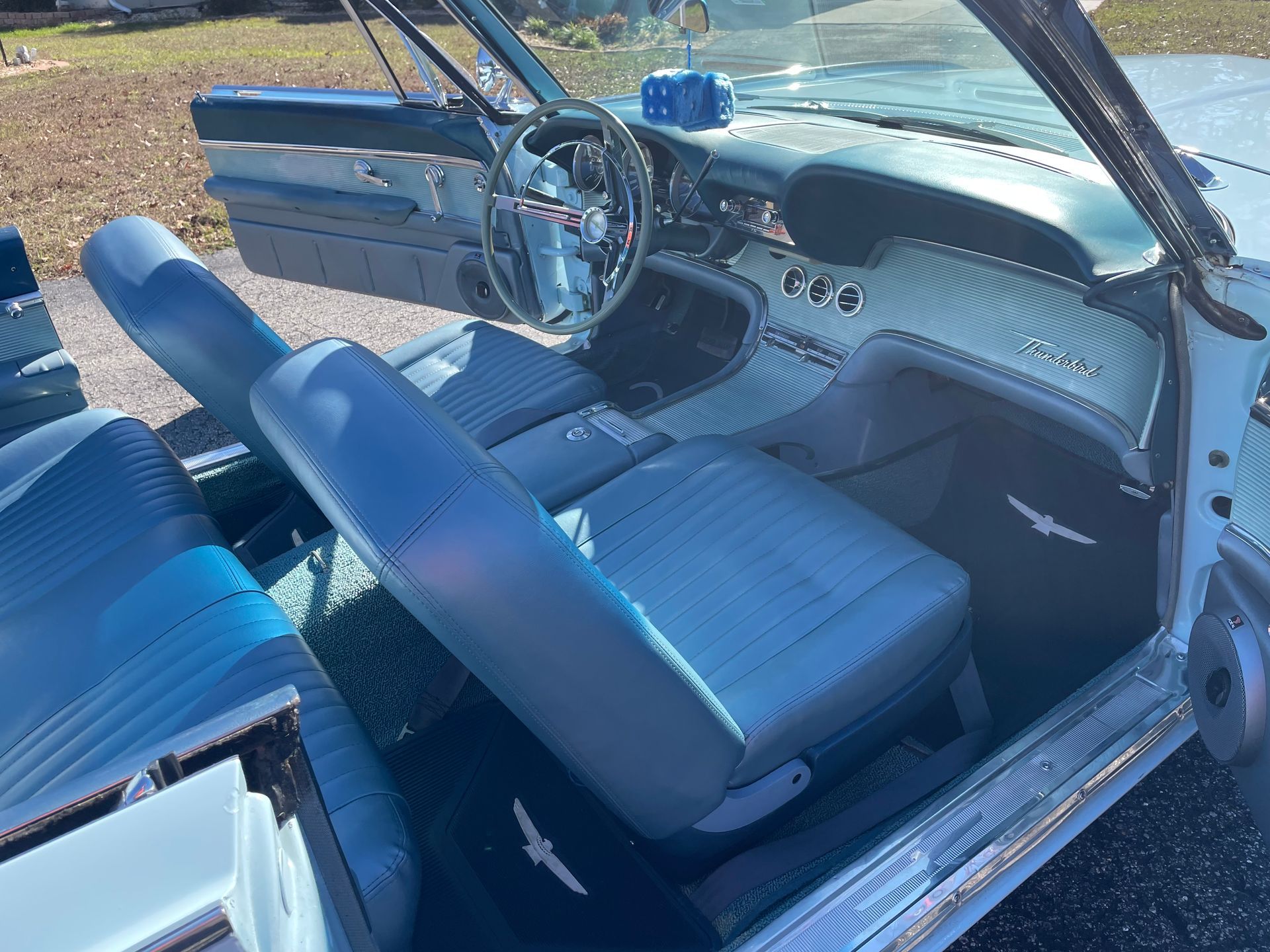 Interior view of a vintage car with blue leather bucket seats, a chrome steering wheel, and a classic dashboard.