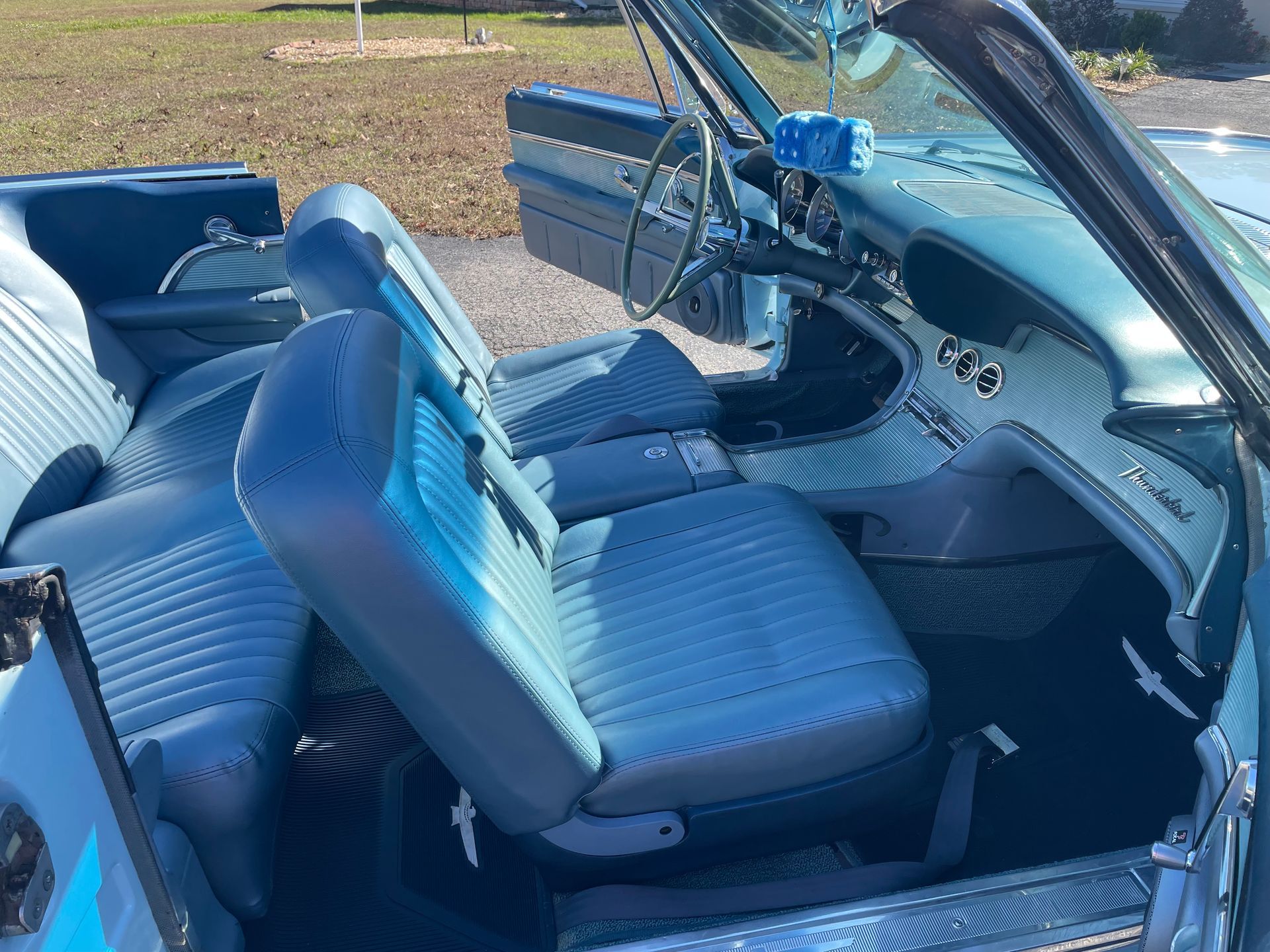 Interior of a light blue vintage convertible with blue leather bucket seats and a matching dashboard.