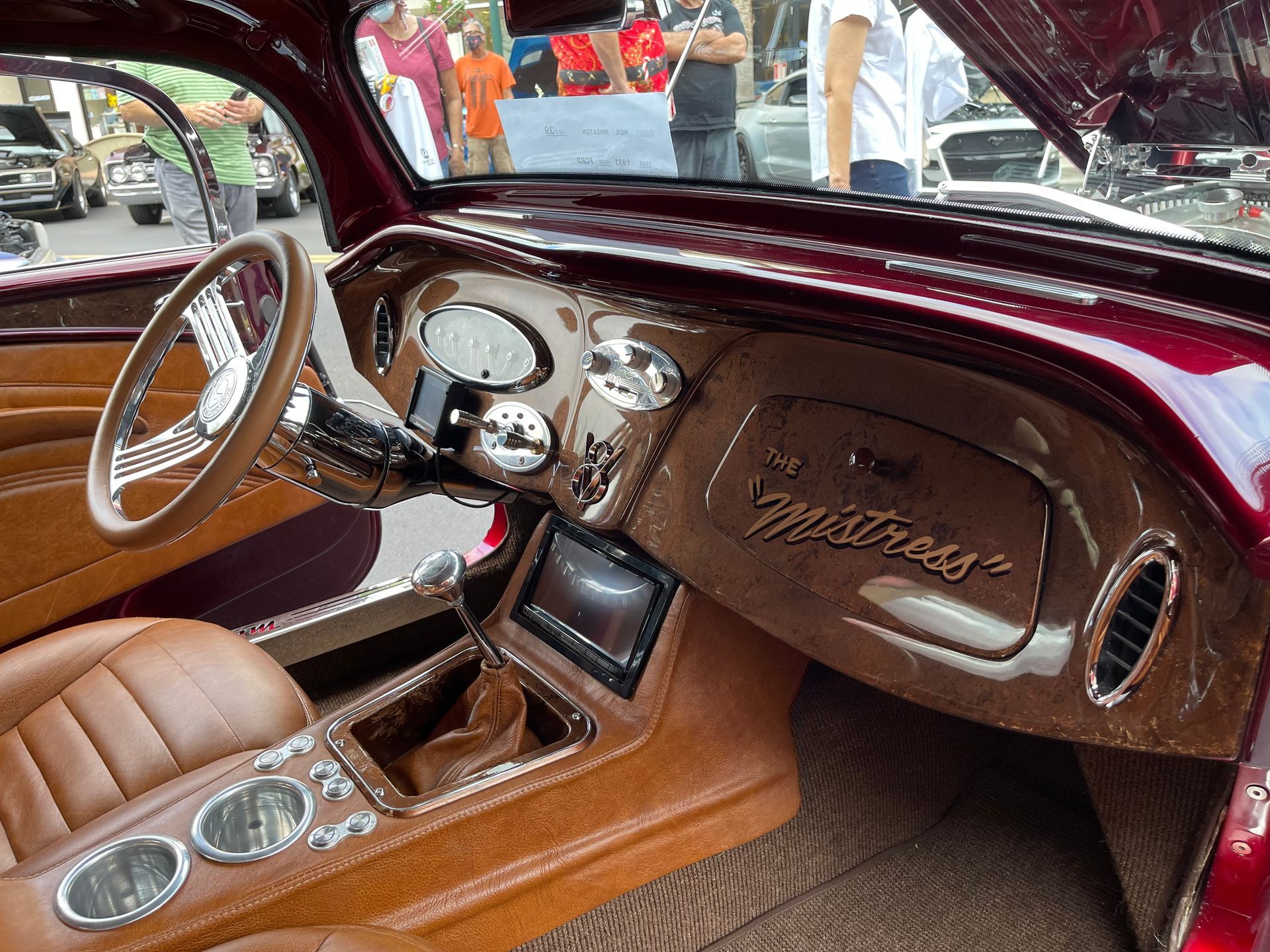 The interior of a classic custom car featuring a brown leather-wrapped dashboard and seats with 