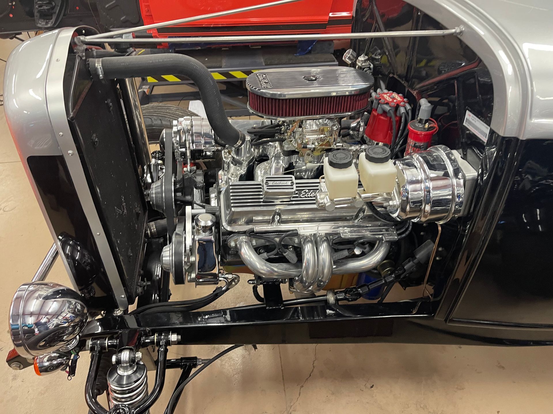 A high-angle view of a shiny, chrome-detailed V8 engine inside a custom silver and black hot rod.