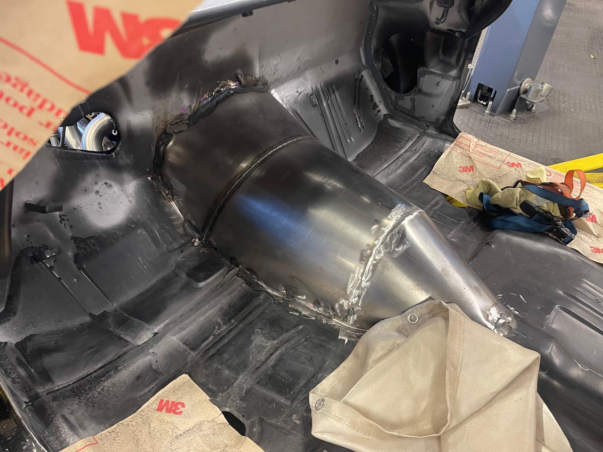 A metal transmission tunnel newly welded into the bare floor of an automotive interior restoration project.