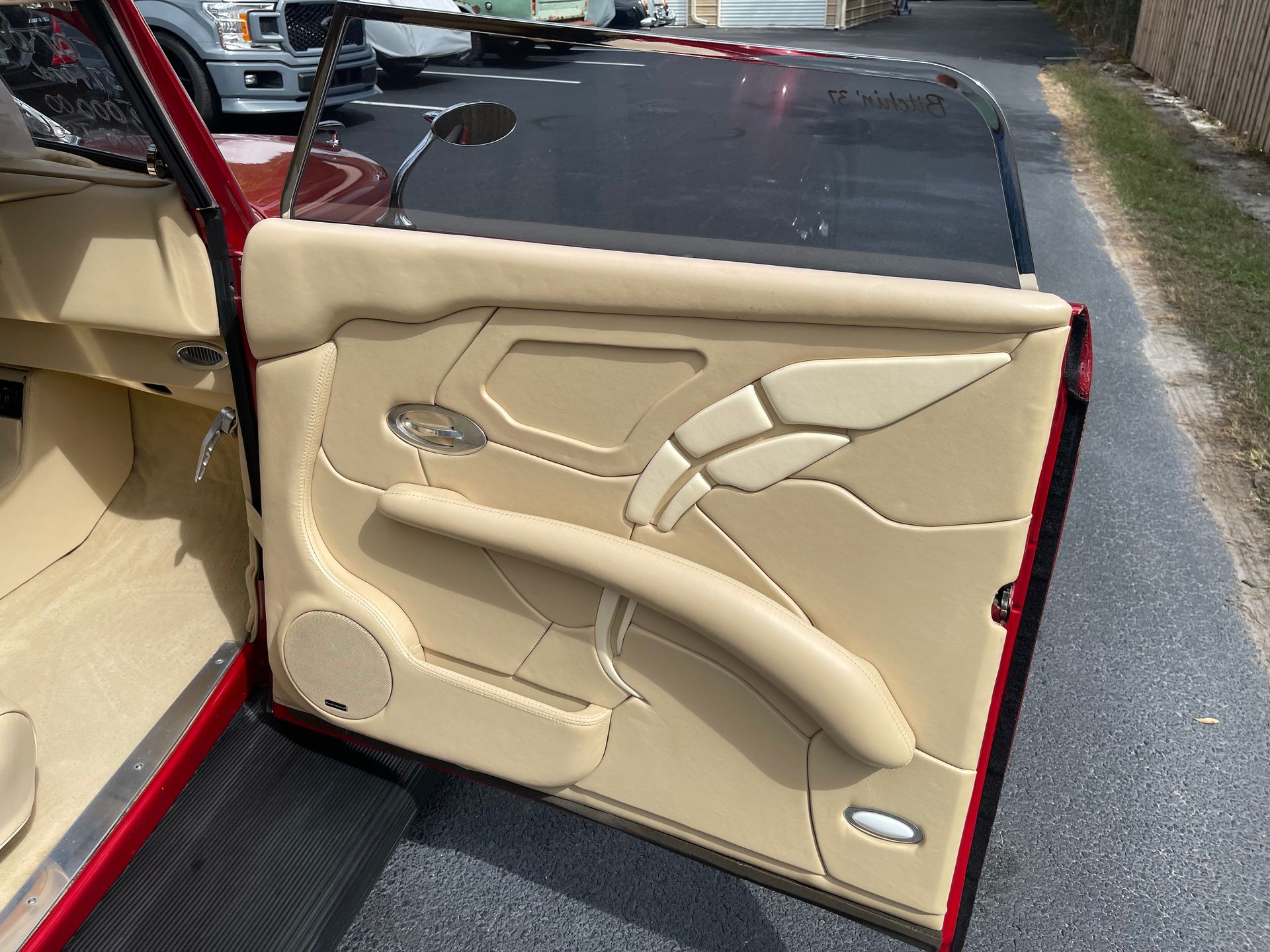 Custom tan leather car door panel with intricate stitching, a speaker, and a built-in armrest.