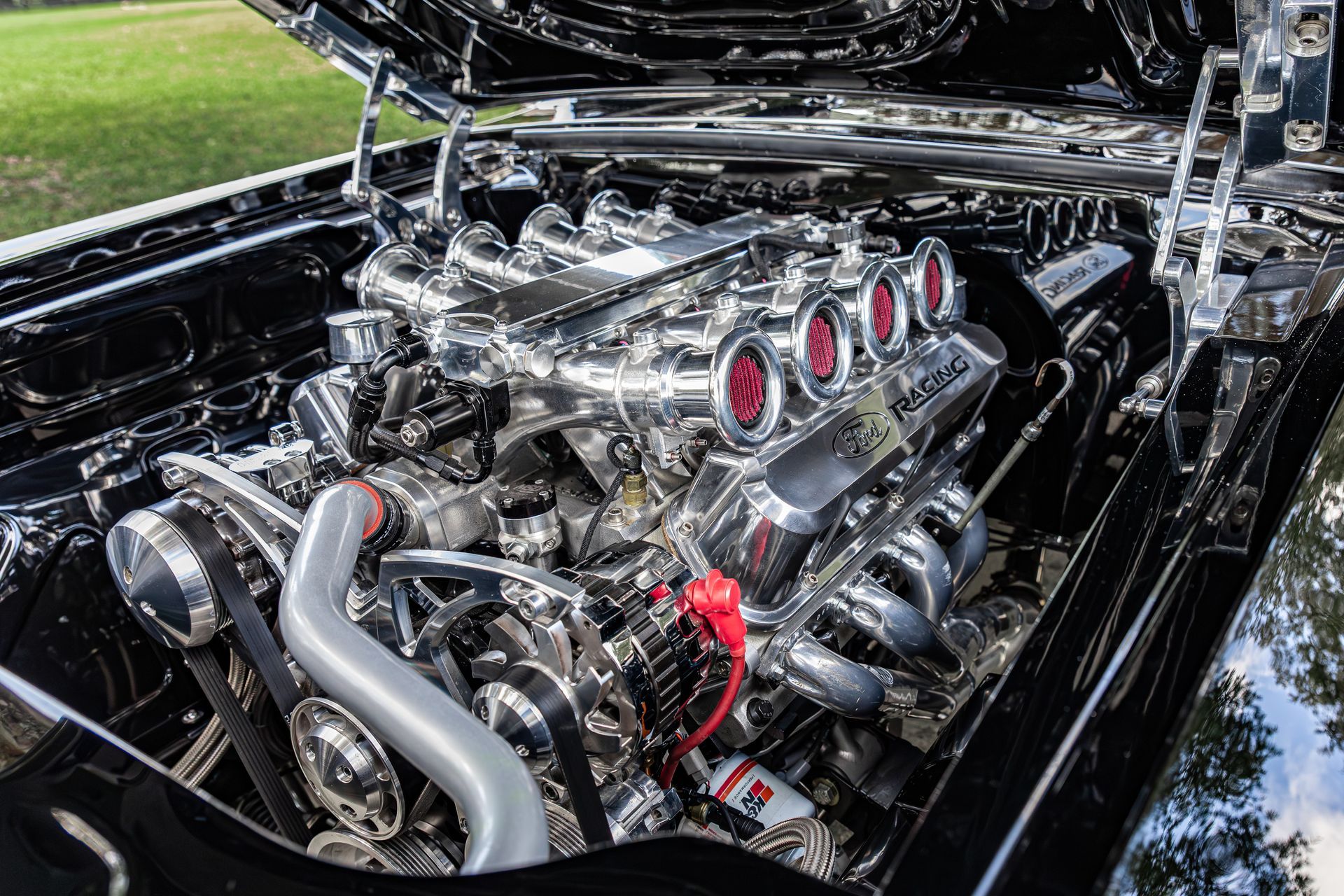 A high-performance V8 engine with a polished chrome finish and red-ringed air intakes under an open car hood.