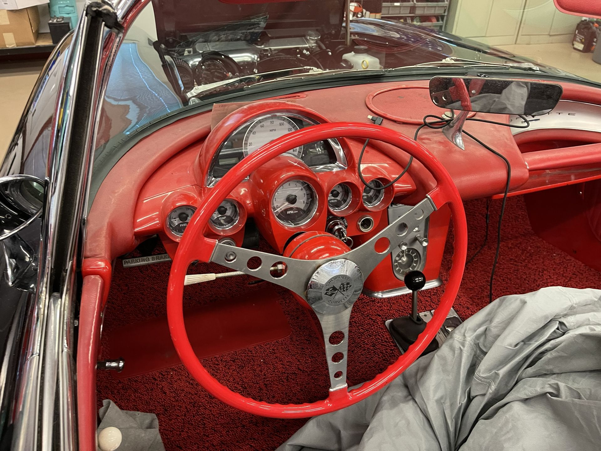 The interior of a classic car with a bright red dashboard, steering wheel, and carpet, captured from the driver's seat.