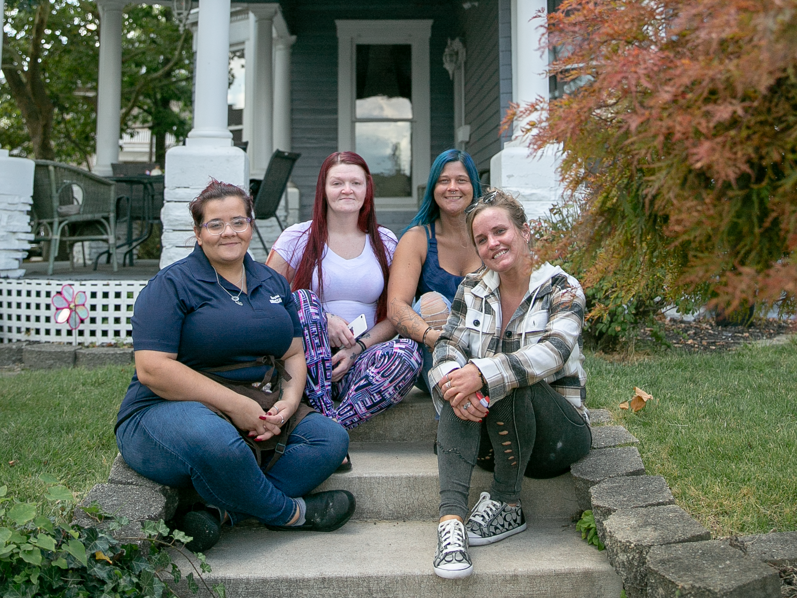 A group of women are sitting on the steps of a house.