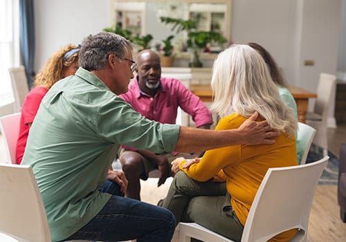 A group of people are sitting in a circle hugging each other.