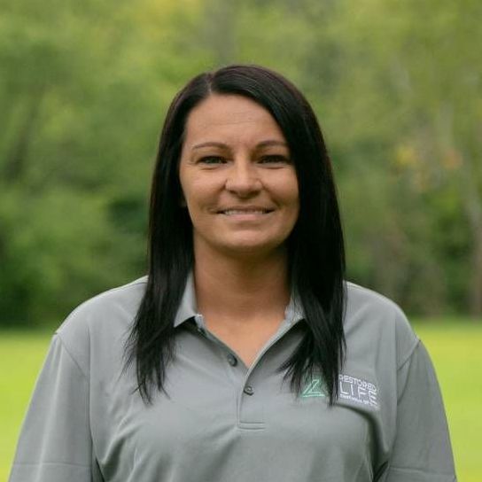 A woman in a grey shirt is smiling for the camera.