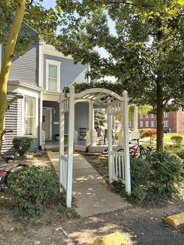 A blue house with a white pergola in front of it.