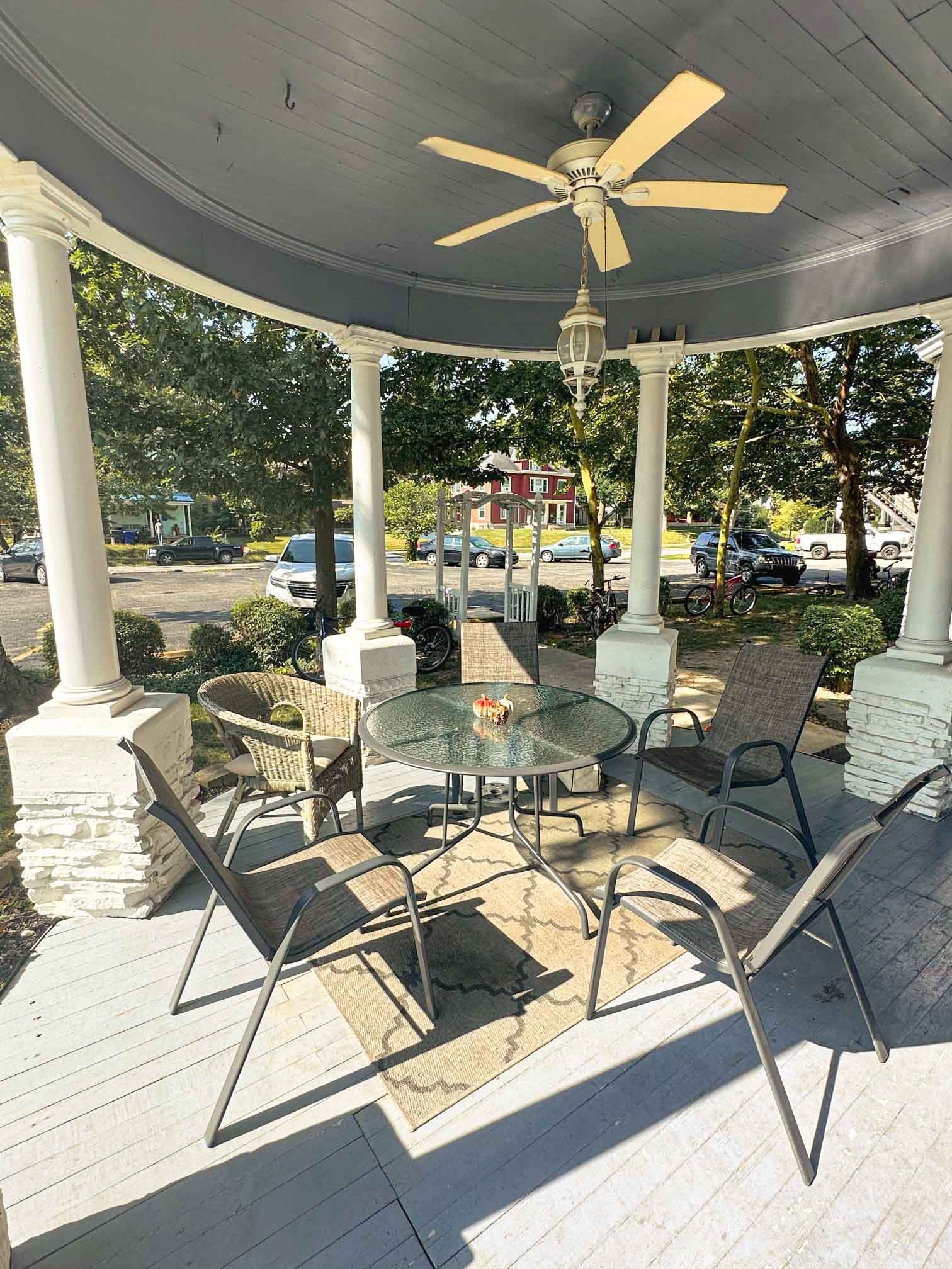 A porch with a table and chairs and a ceiling fan.