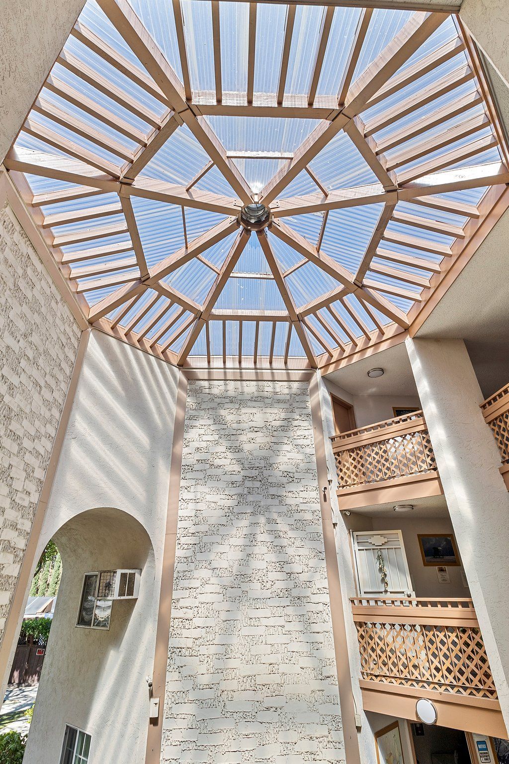 A multi-story atrium with a wooden octagonal skylight casting geometric shadows on a textured, light-colored stone wall at Parkview Apartments.