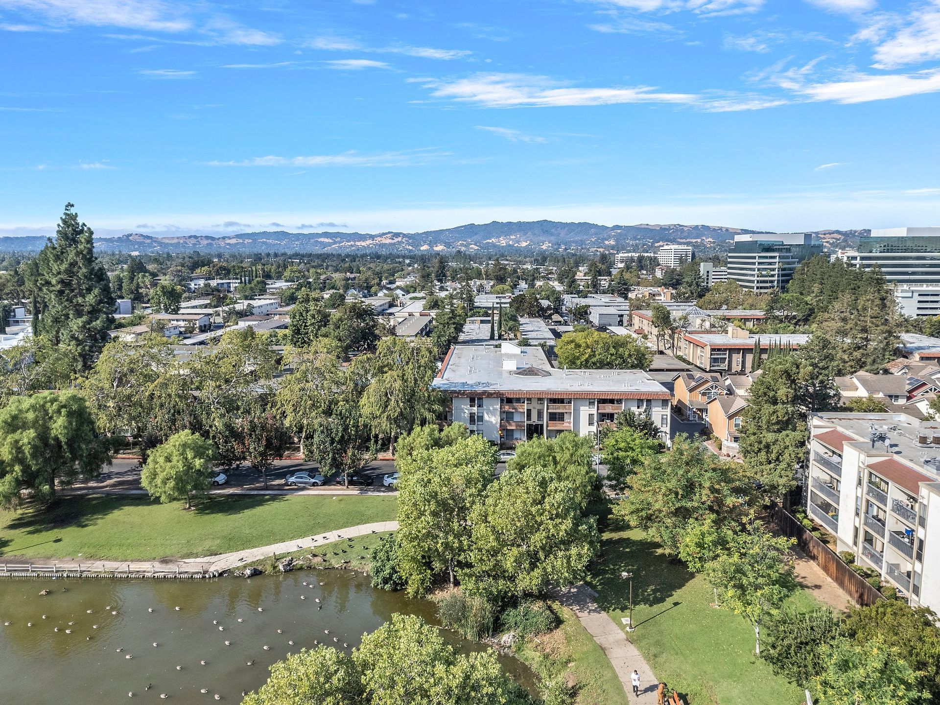 A sidewalk leads to the entryway of a multi-story apartment building with balconies, wood railings, and green landscaping at Parkview Apartments.