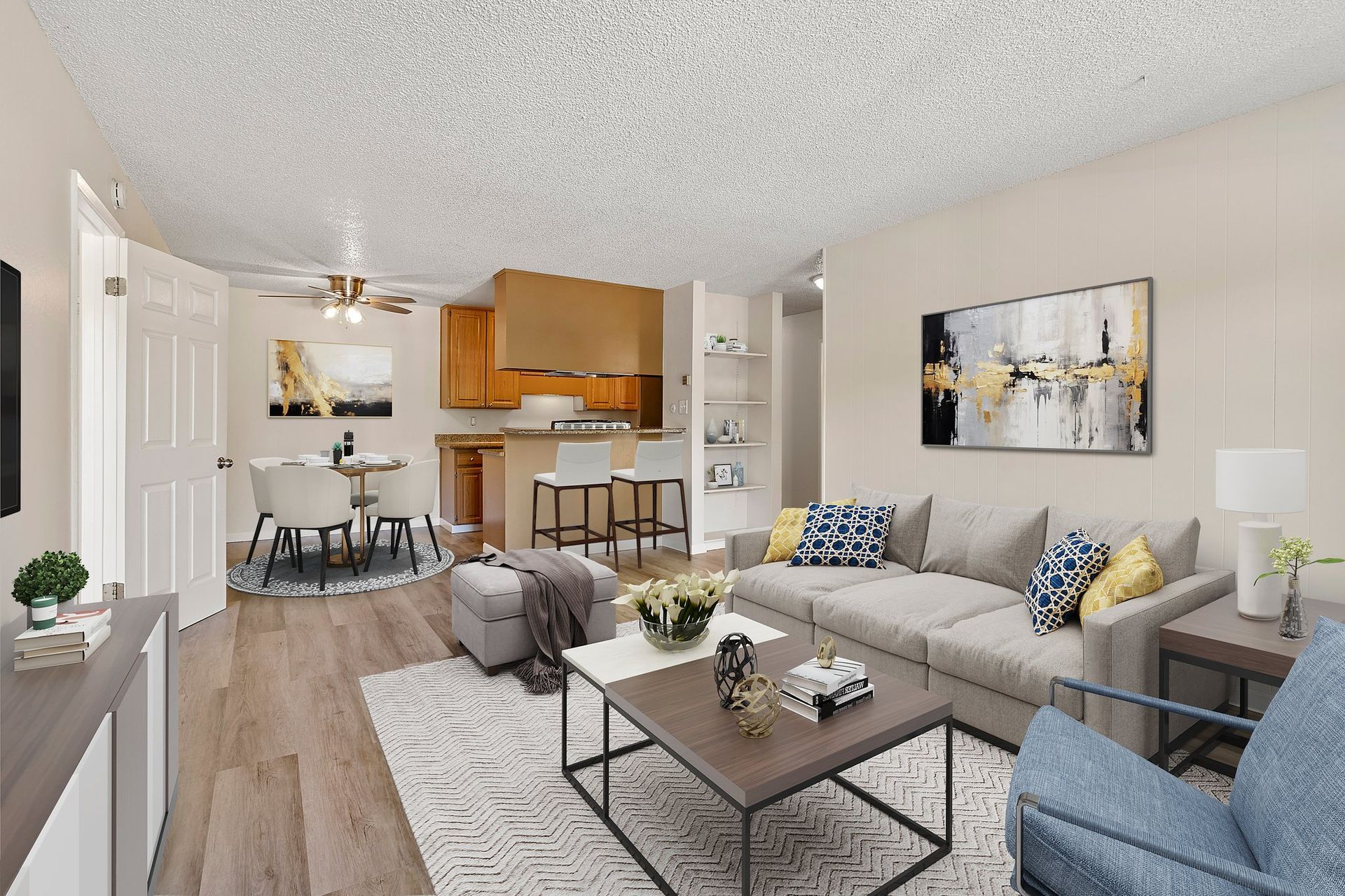 A bright, modern open-plan apartment featuring a cozy living room with a gray sofa and a dining area beside a kitchen at Parkview Apartments.