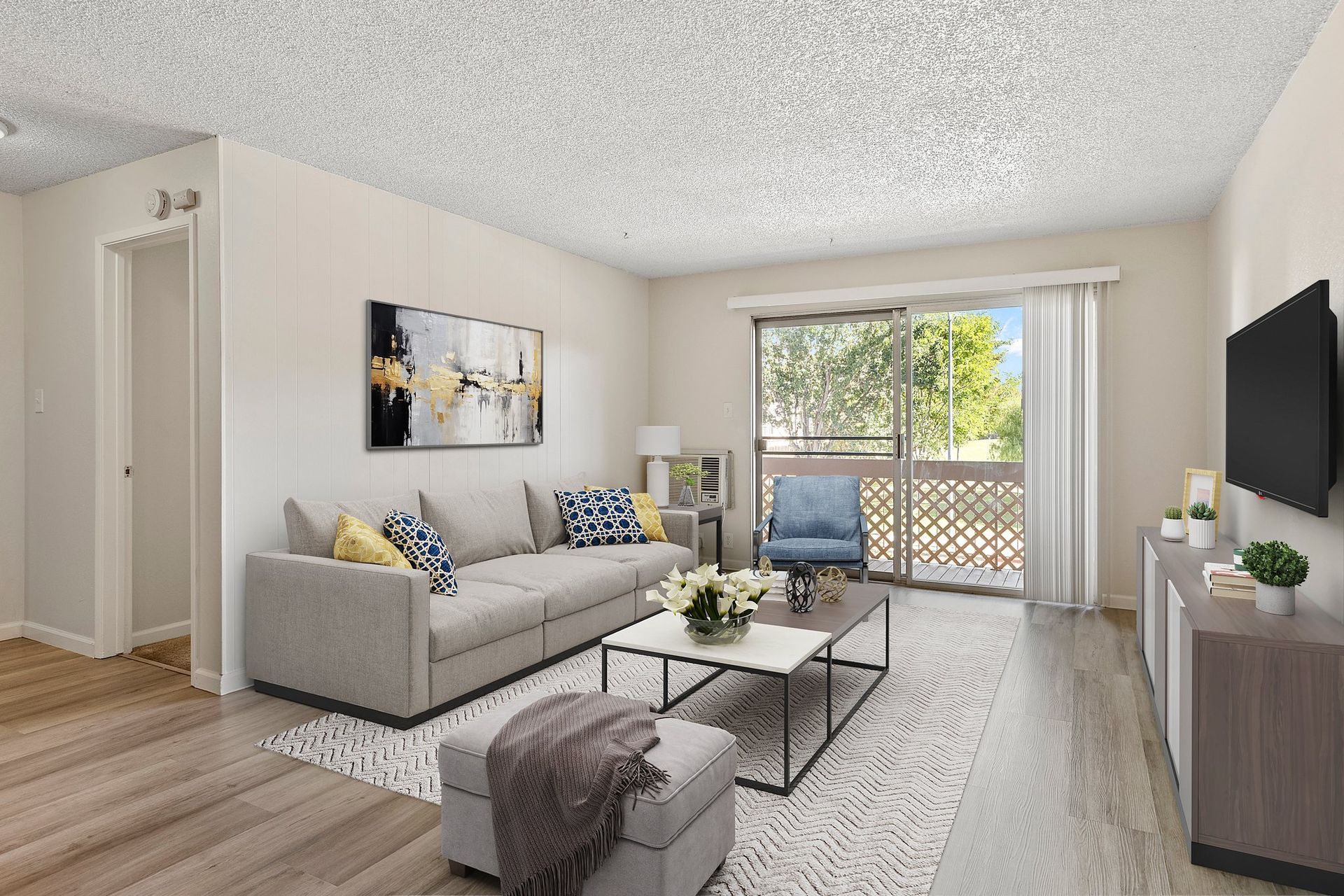 Bedroom with a gray bed, dark gray bedding, dresser with a wall-mounted TV, closet, ceiling fan, and view of a kitchen at Parkview Apartments.