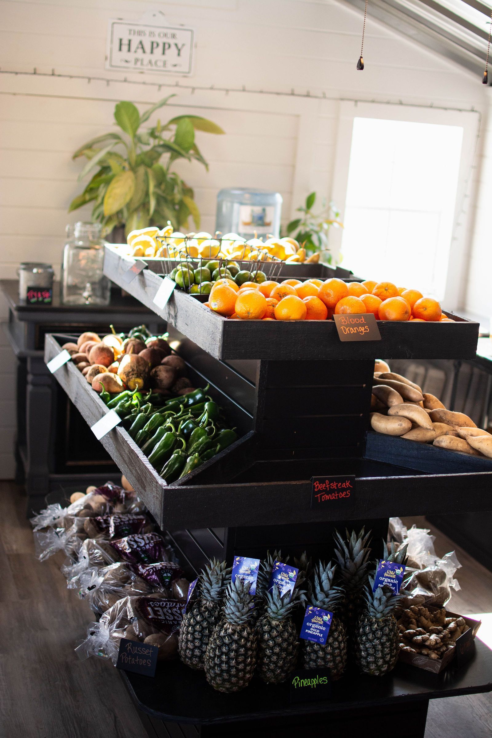 Produce stand with stacked black wooden shelves holding various fruits and vegetables.