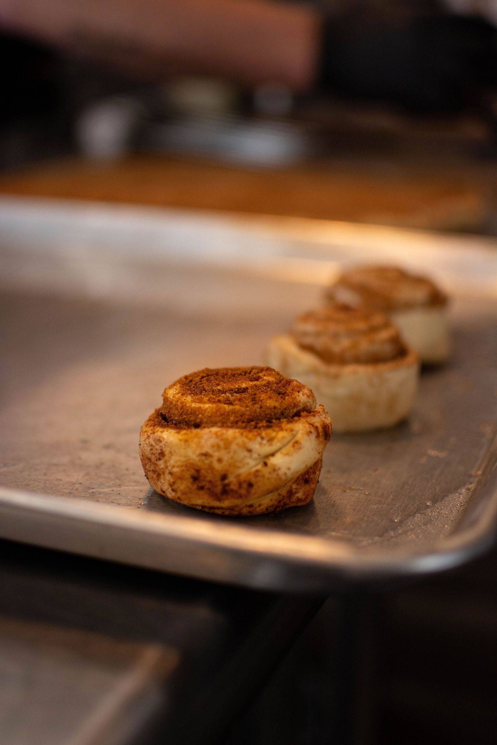Three cinnamon rolls on a metal baking sheet, in close-up shot.