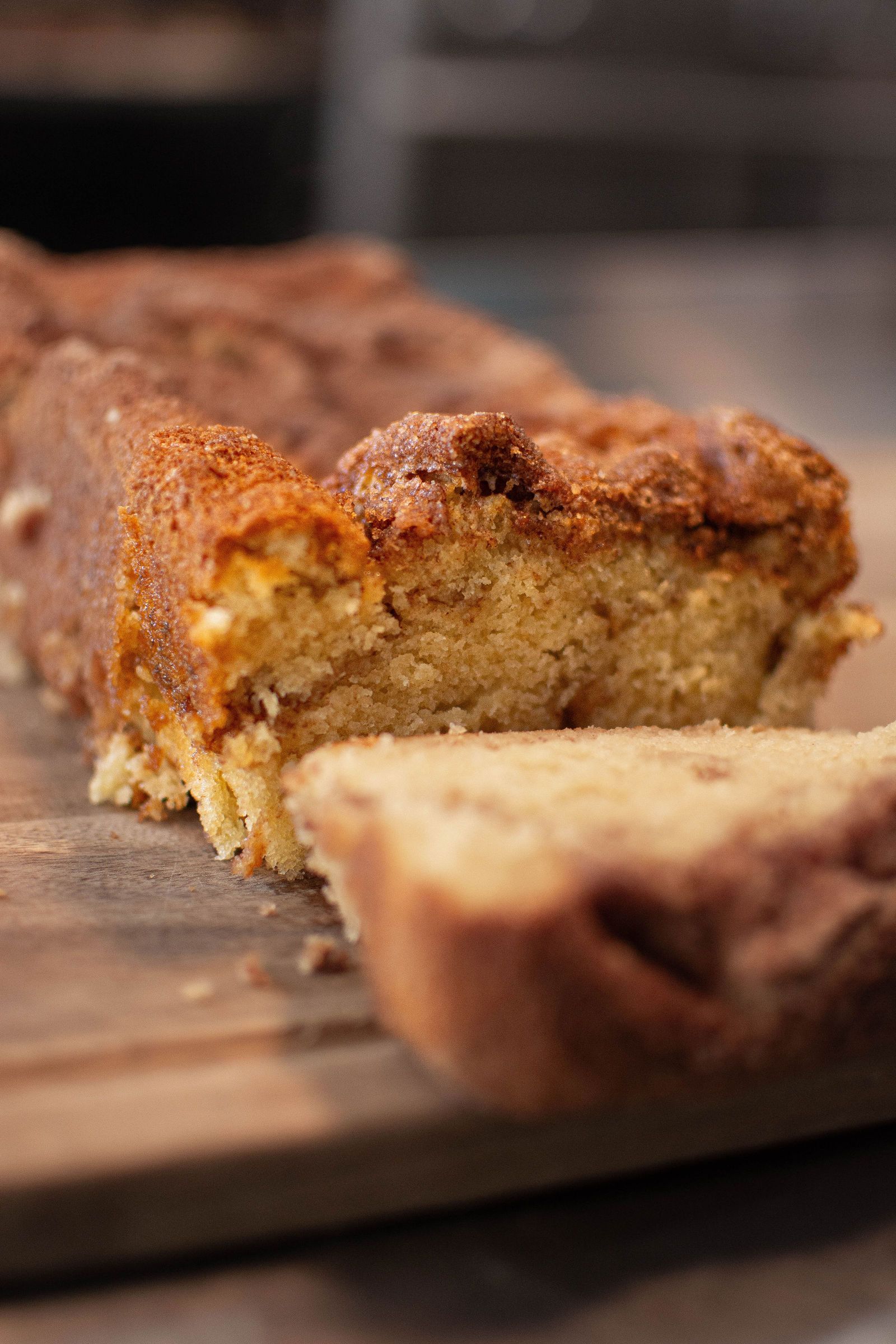 Sliced cinnamon swirl bread on a wooden board; close-up shows textured crumb and topping.
