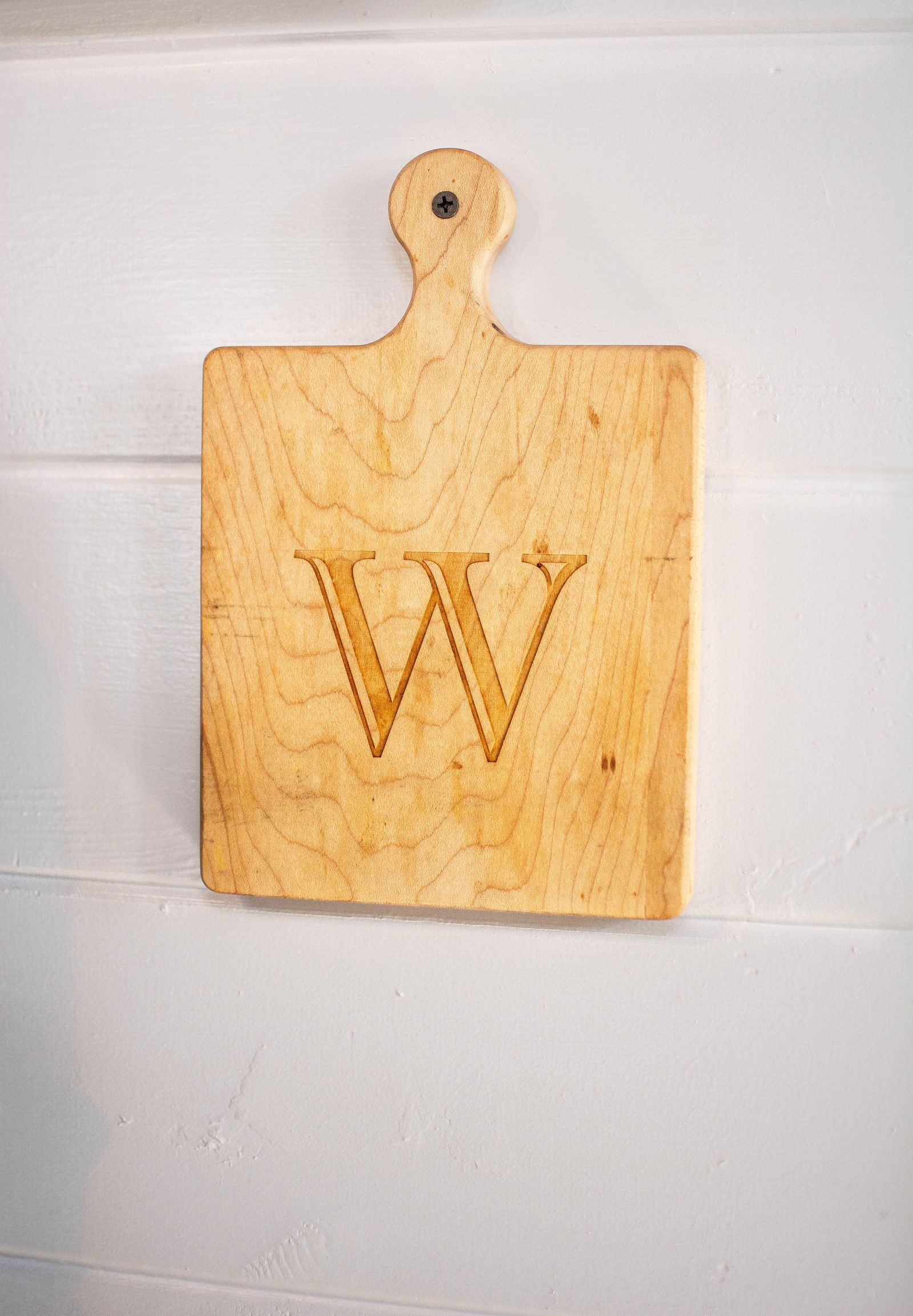 Wooden cutting board with handle, etched with the letter 