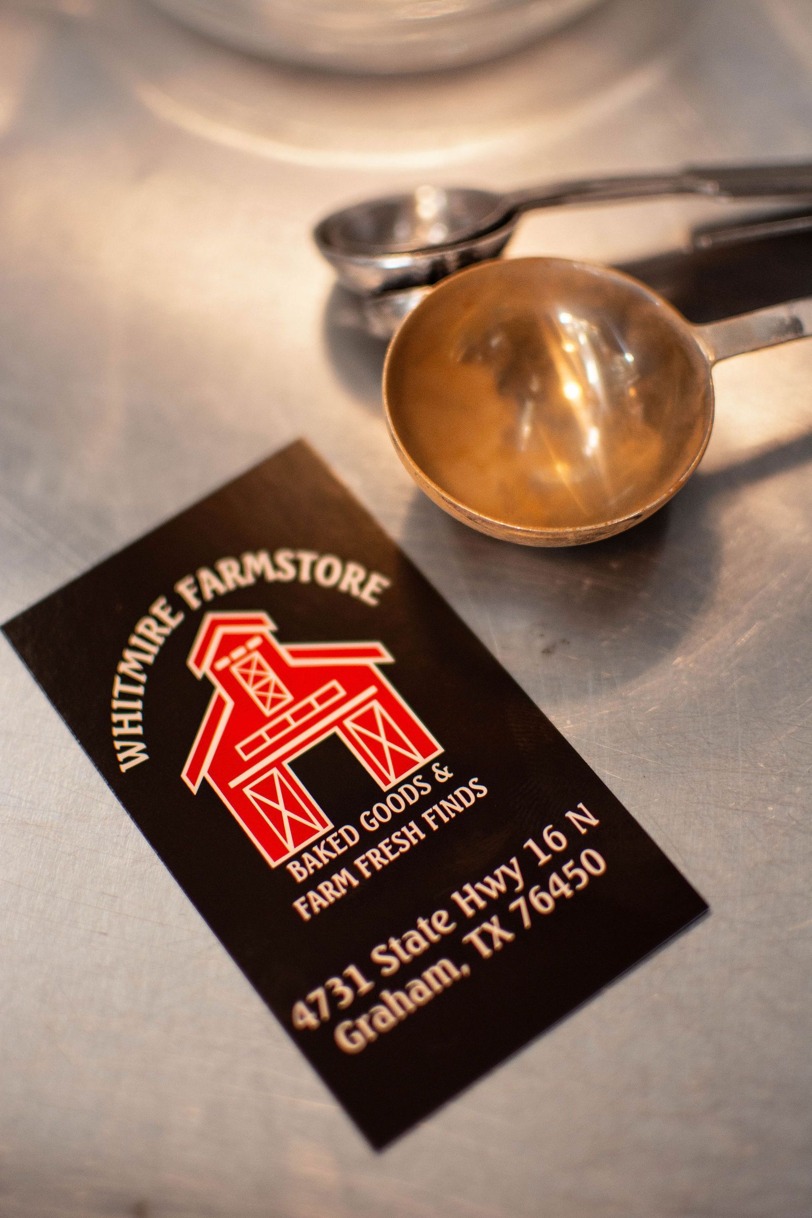 Business card for Whitmire Farmstore with a red barn logo, and measuring spoons.