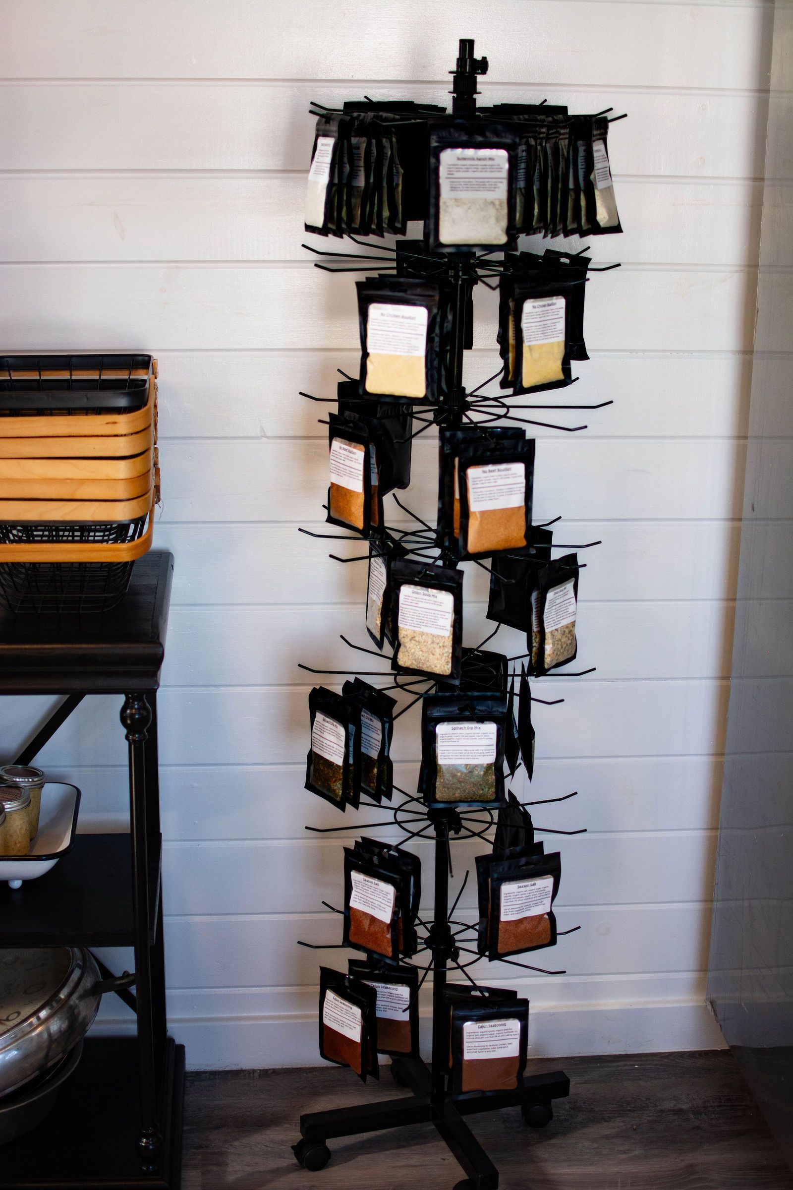 Black metal rotating display stand with various spice packets.