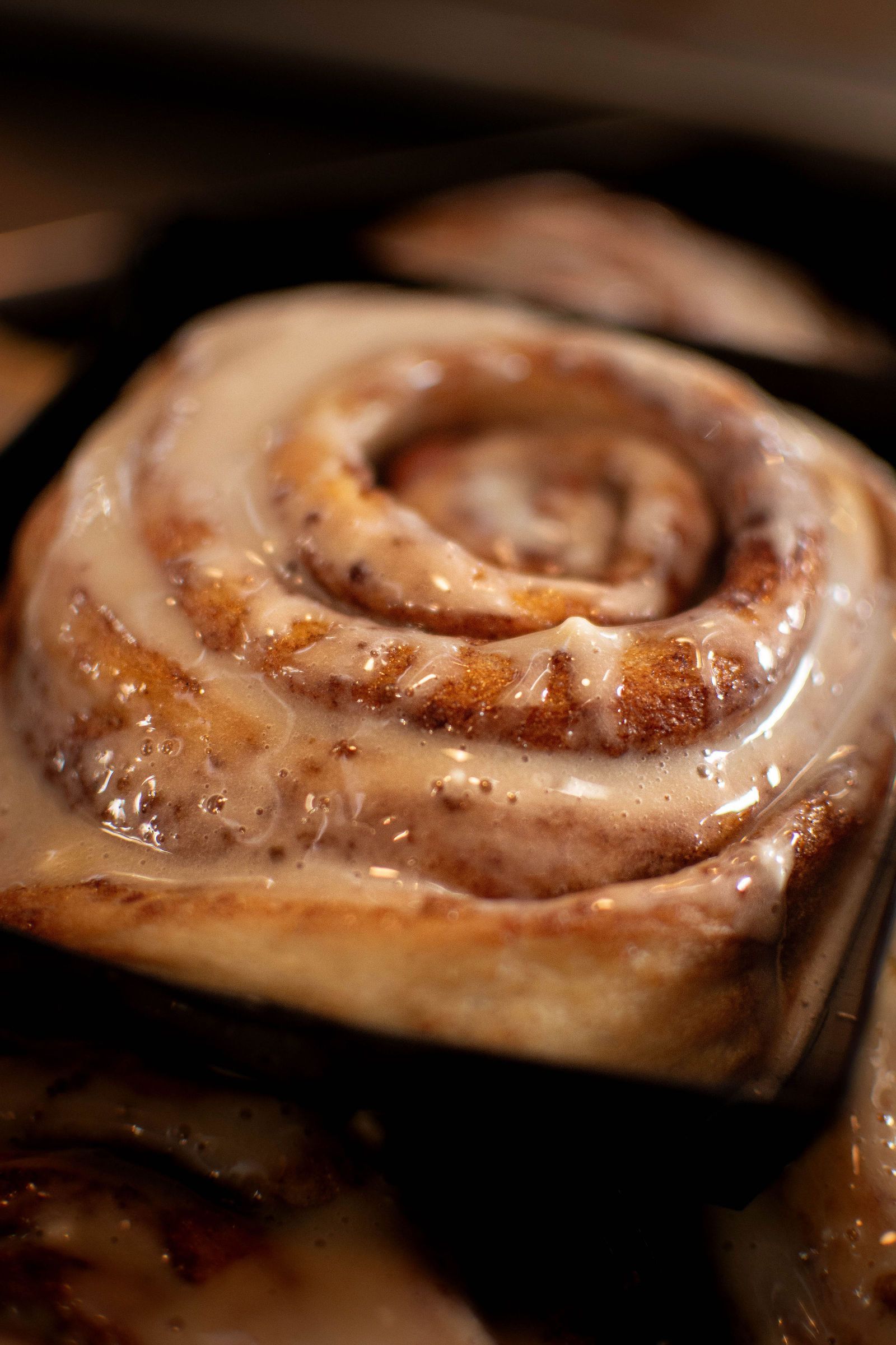Cinnamon roll with a glazed icing in a baking pan.