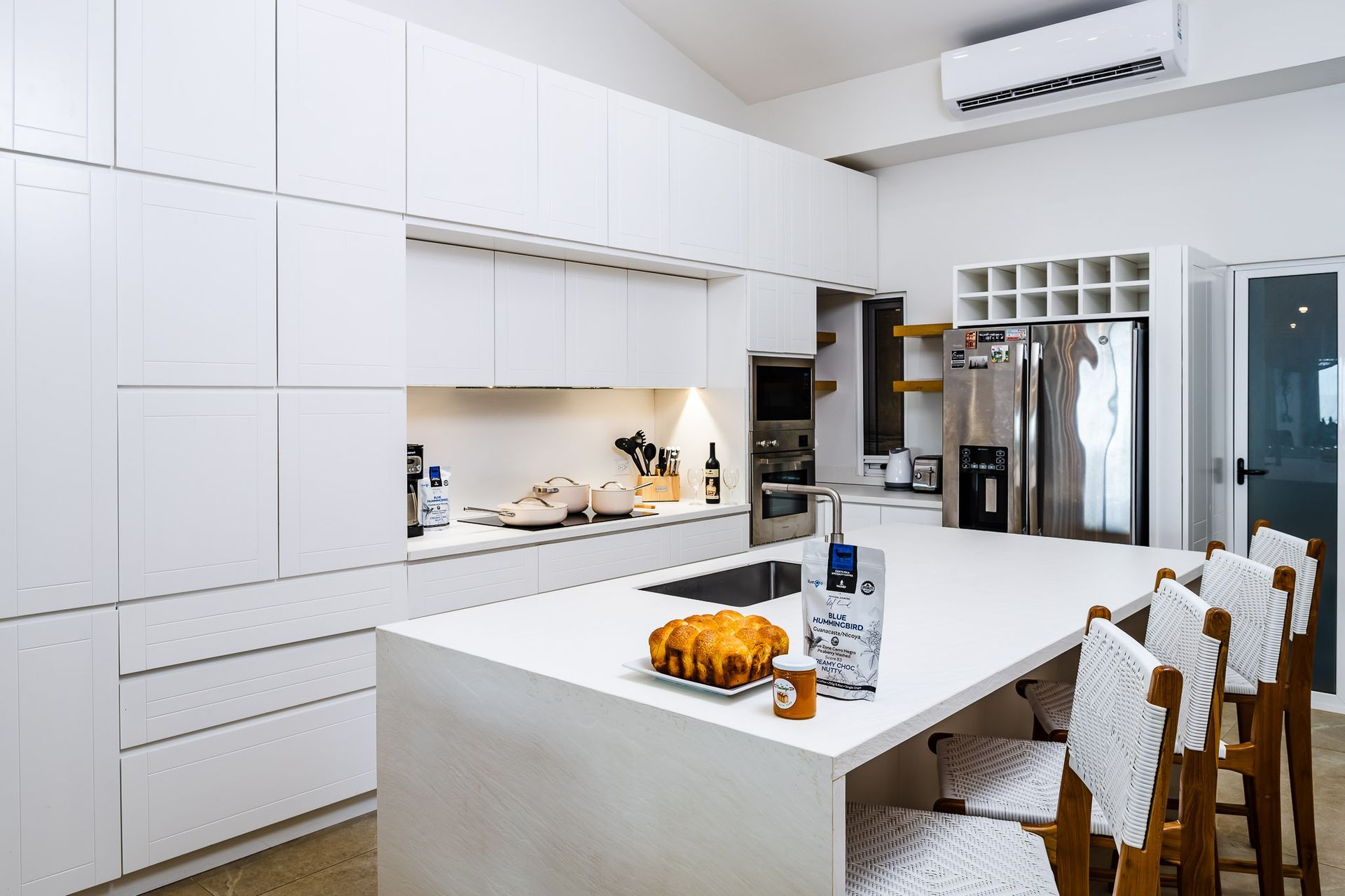 A kitchen with white cabinets , stainless steel appliances , and a large island.