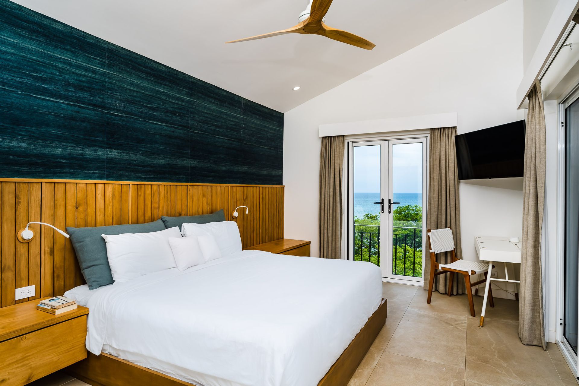 A hotel room with a large bed and a ceiling fan