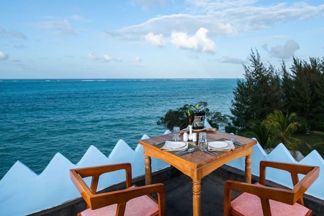 A table and chairs on a balcony overlooking the ocean.