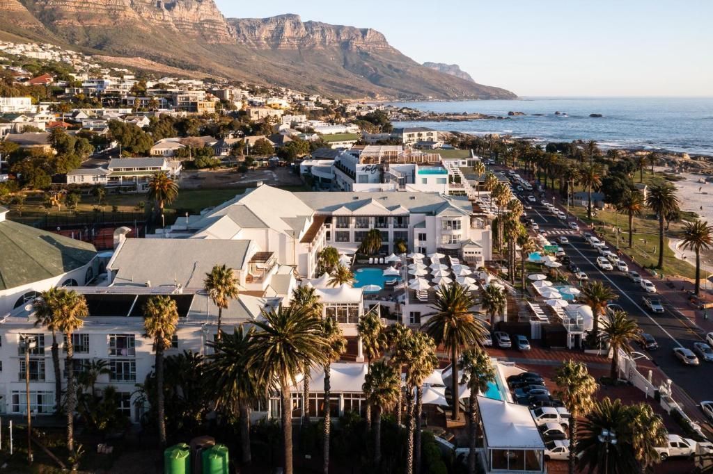 An aerial view of a beachside hotel in Cape Town, South Africa with palm trees and mountains.