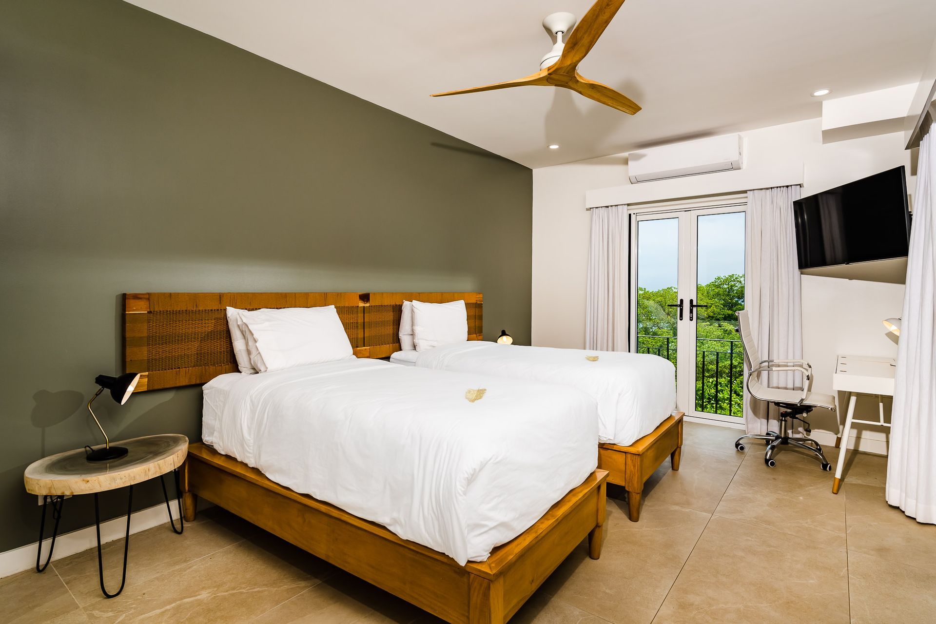 A hotel room with two beds , a desk and a ceiling fan.