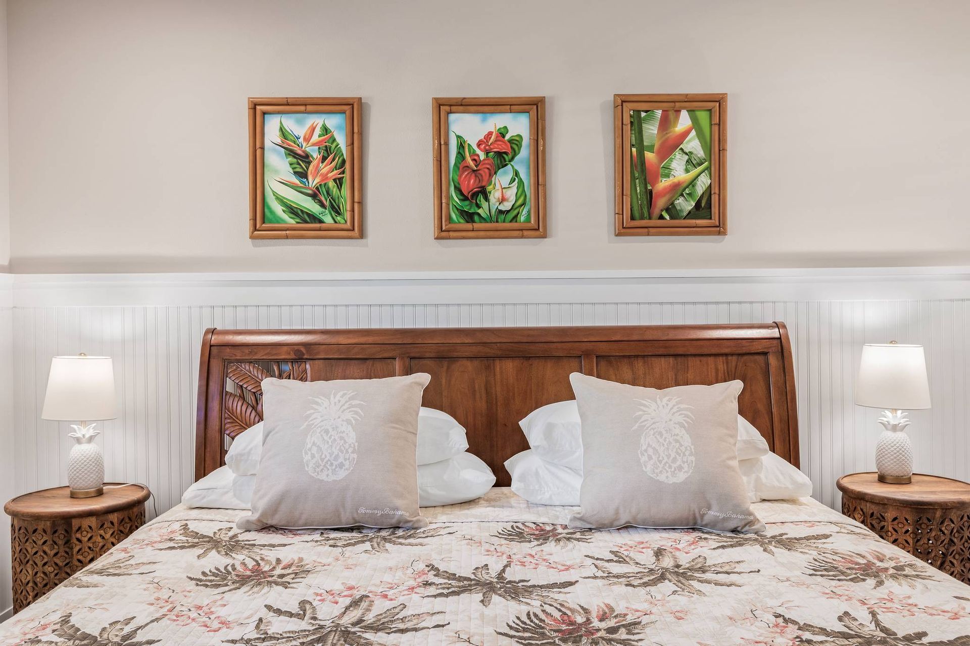 There are three paintings on the wall above the bed.