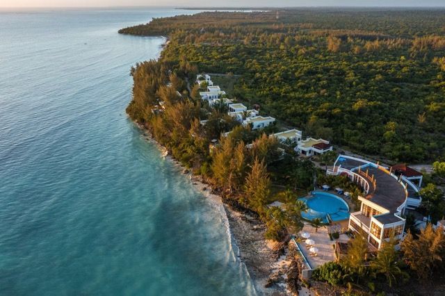 An aerial view of a resort on a tropical island next to the ocean.