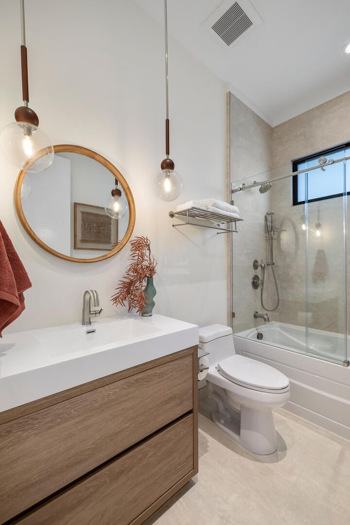 A bathroom with a toilet , sink , mirror and bathtub.