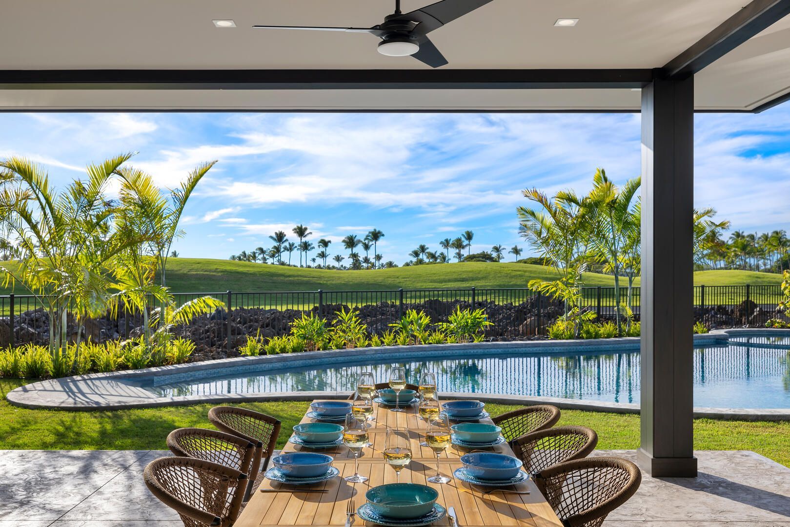 A long dining table with a view of a swimming pool and a golf course.